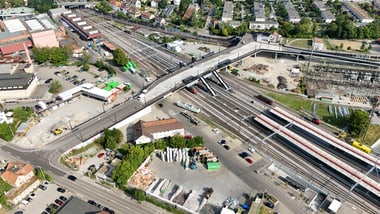 Luftaufnahme eines Bahnhofs mit mehreren Gleisen und Gebäuden.