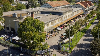 Luftaufnahme eines Gebäudes mit Marktständen und Bäumen.