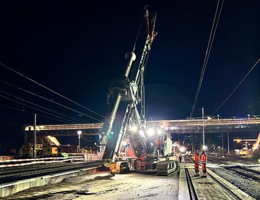 Nachtszene einer Baustelle mit grossem Kran und Arbeiter.